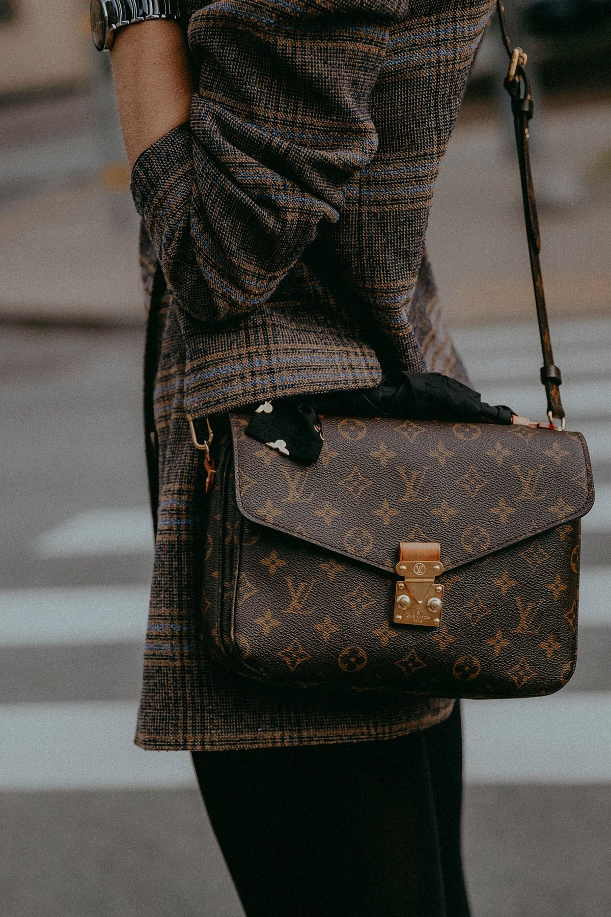 Louis Vuitton monogram Pochette Metis worn over a plaid coat